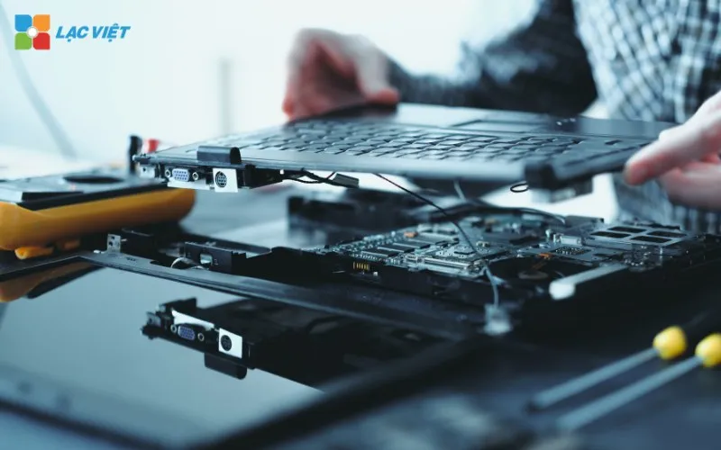 Kỹ thuật viên tiến hành tháo bàn phím cũ ra khỏi laptop và thay mới